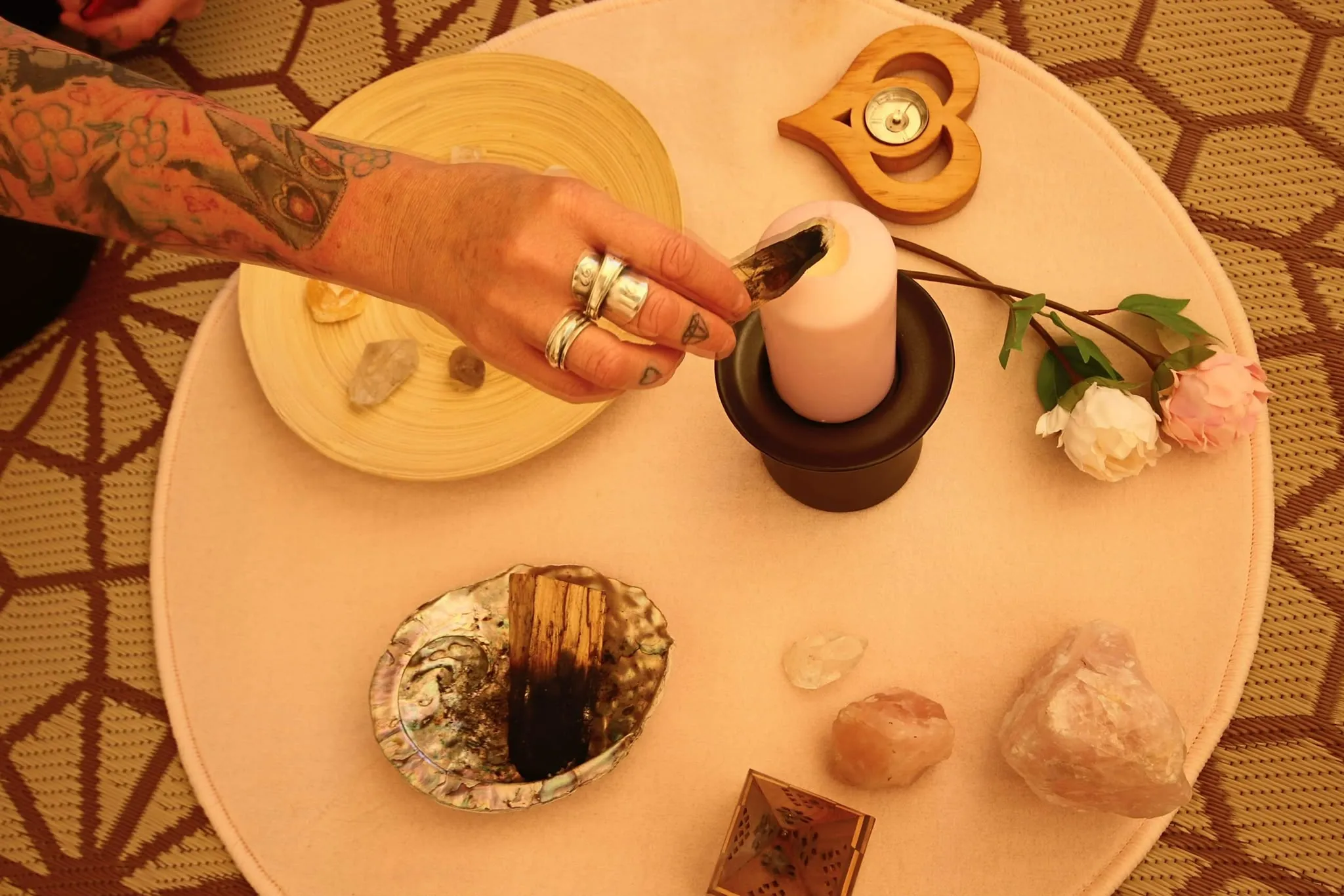 Hands lighting a candle on a ritual table with crystals and roses
